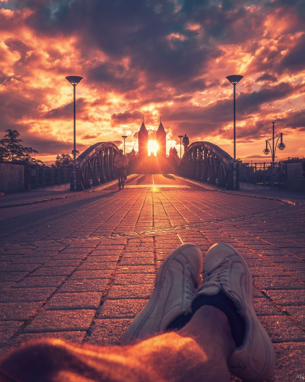 Person entspannt auf einer Brücke mit Blick auf den Dom